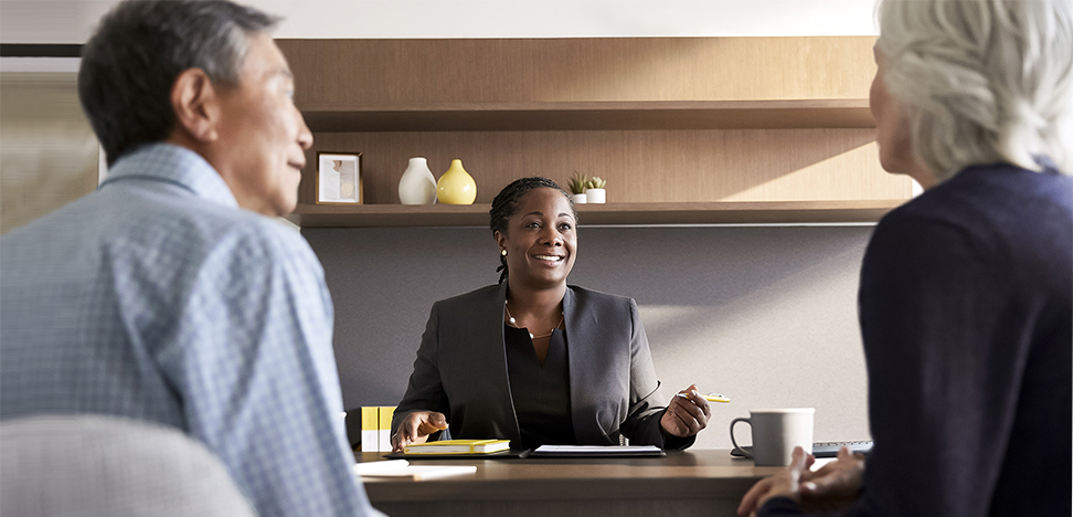 Female financial advisor with client couple at her desk