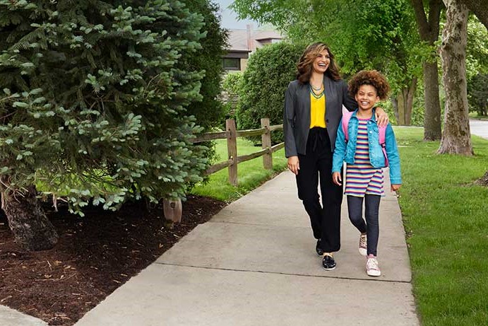 Business woman stares out with hope at home with spouse and child in background of kitchen.