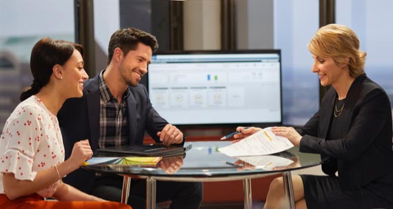 Un couple rencontre une femme d’affaires qui examine des documents.