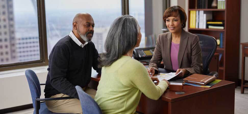 An older couple seated at the desk of a financial advisor.