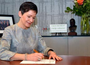 Penny Pennington, associée directrice, signe un document à son bureau.