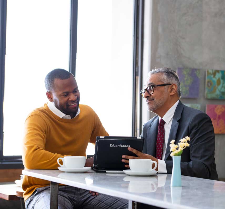Two professional men having a discussion in an office using an Edward Jones's tablet.