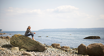 Woman relaxing on a rocky beach.