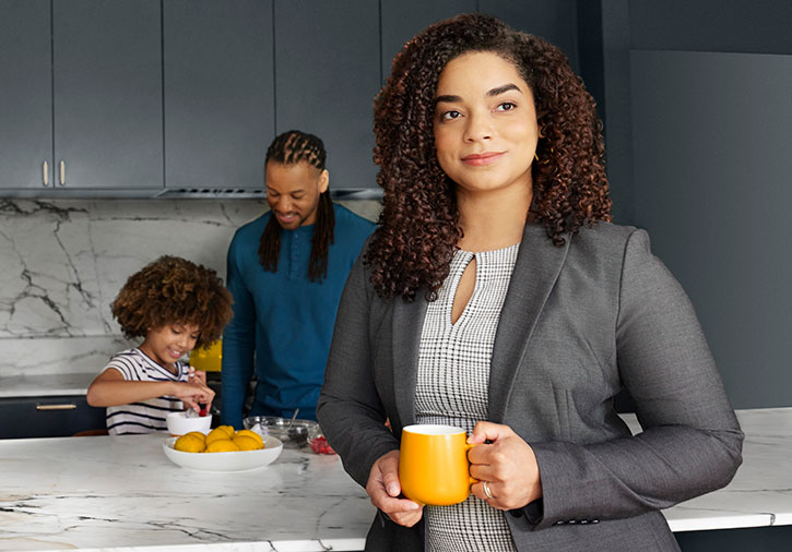 Business woman stares out proudly while man and young child make breakfast